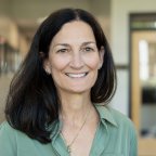 Sharon Wise, with shoulder-length hair and waering a green top, smiles at the camera.