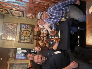 Happy Utica alums sit together for a round of drinks at The Beer Hub in Utica. A Utica University tablecloth is on the table.